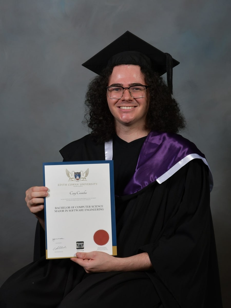 Holding my testamur in graduation regalia
